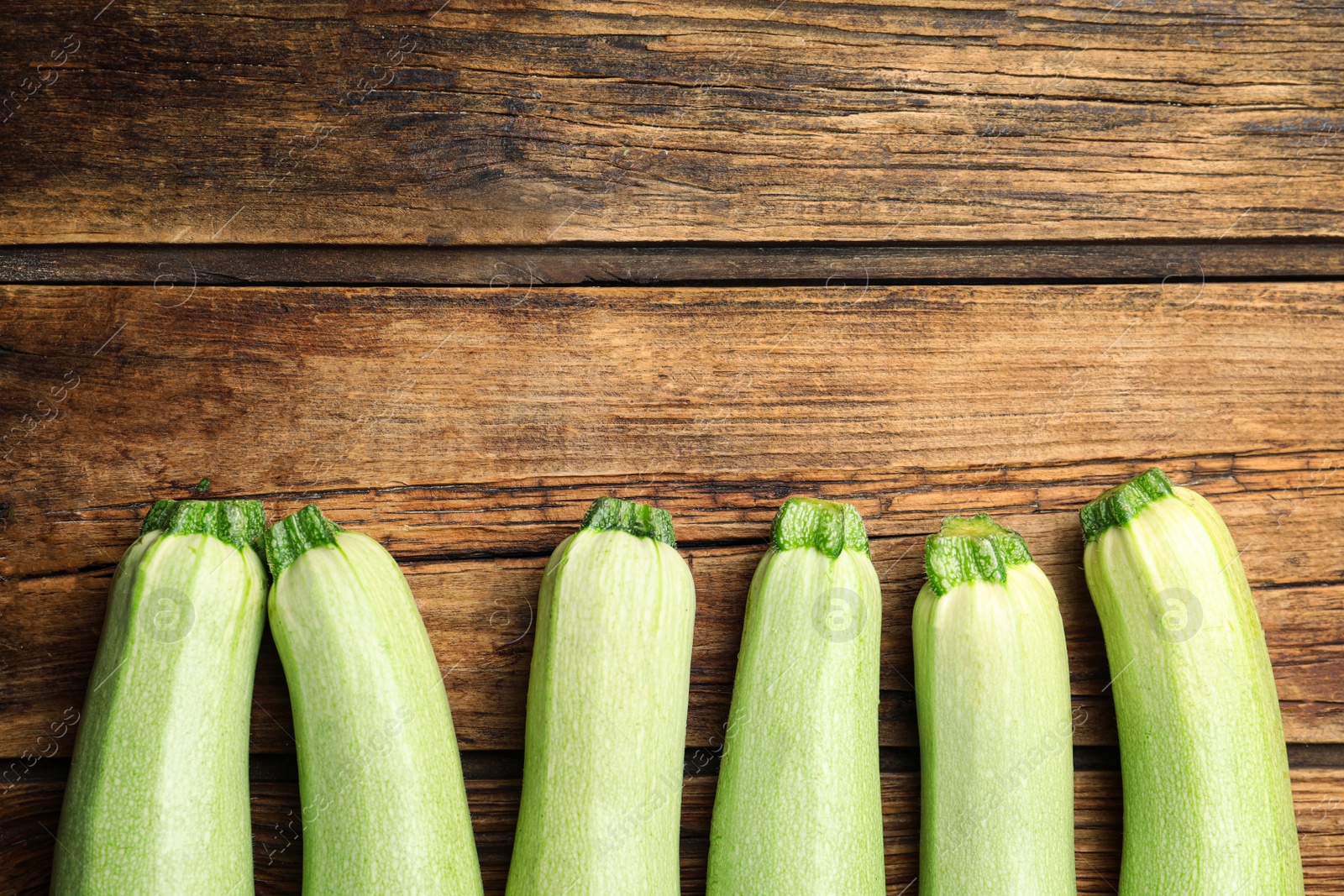 Photo of Raw green zucchinis on wooden table, flat lay. Space for text