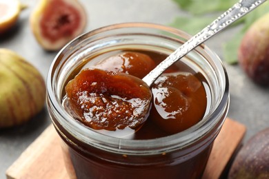 Photo of Jar of tasty sweet fig jam on table, closeup