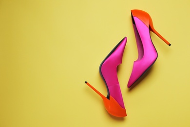 Pair of beautiful shoes on yellow background, top view. Space for text