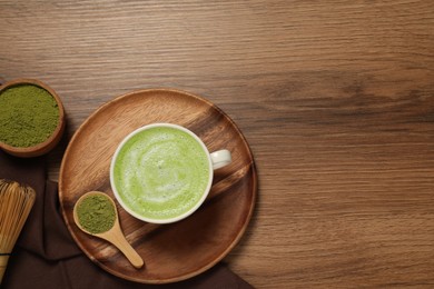 Photo of Cup of fresh matcha latte and powder on wooden table, flat lay. Space for text