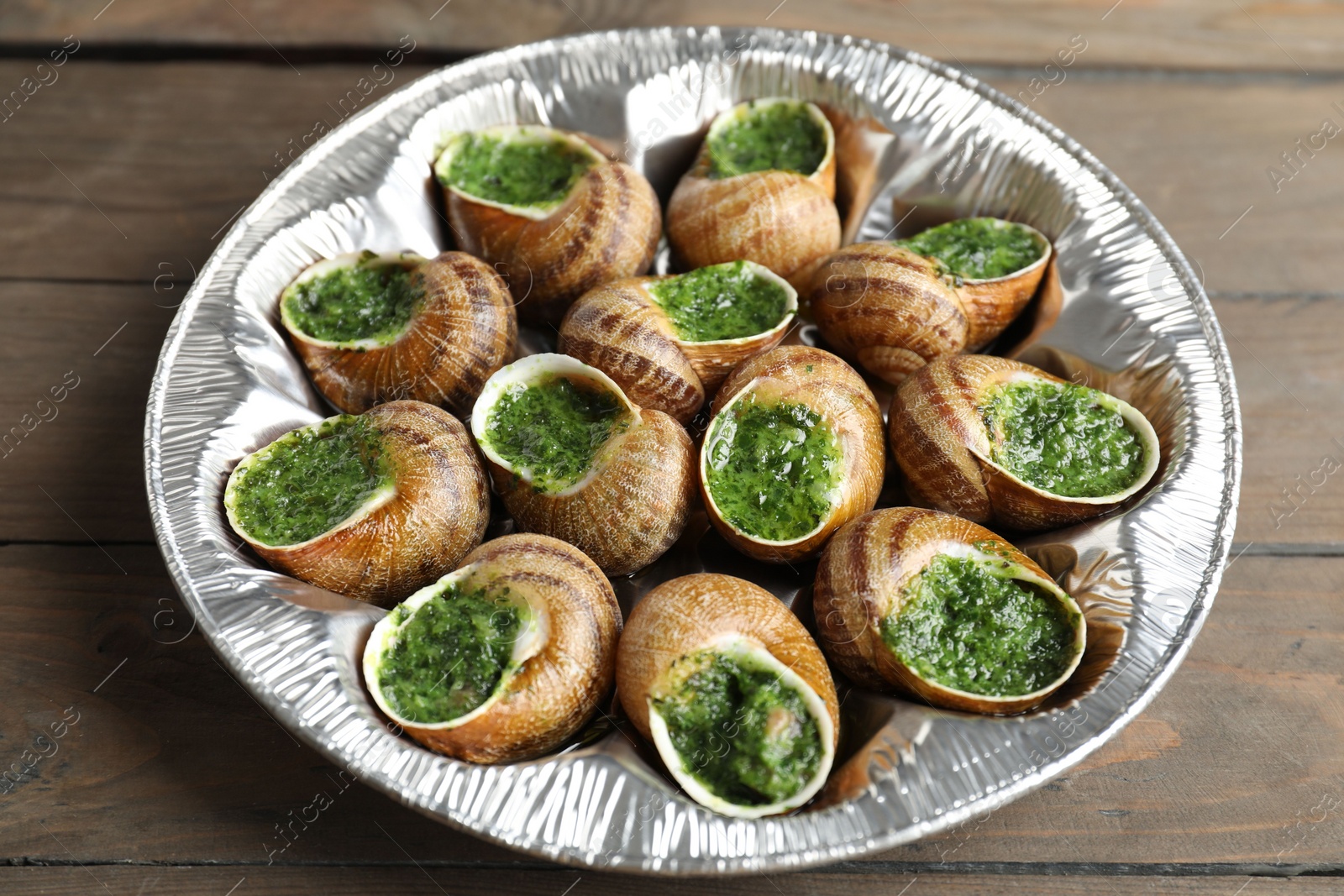 Photo of Delicious cooked snails on wooden table, closeup