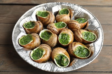 Delicious cooked snails on wooden table, closeup
