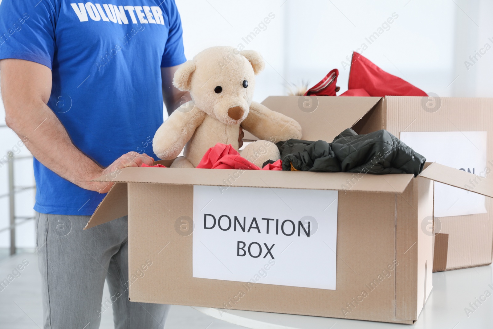 Photo of Male volunteer collecting donations at table indoors