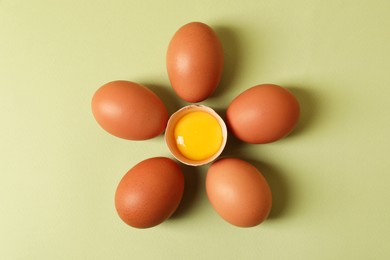 Flower made with cracked and whole chicken eggs on olive background, flat lay