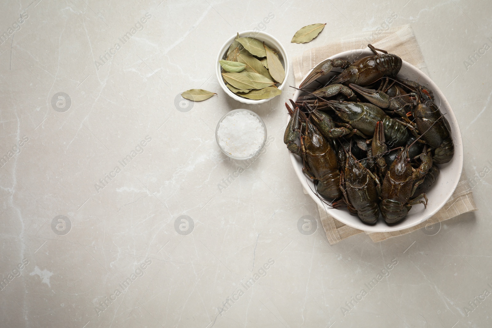 Photo of Fresh raw crayfishes with bay leaves and salt on light grey table, flat lay. Space for text