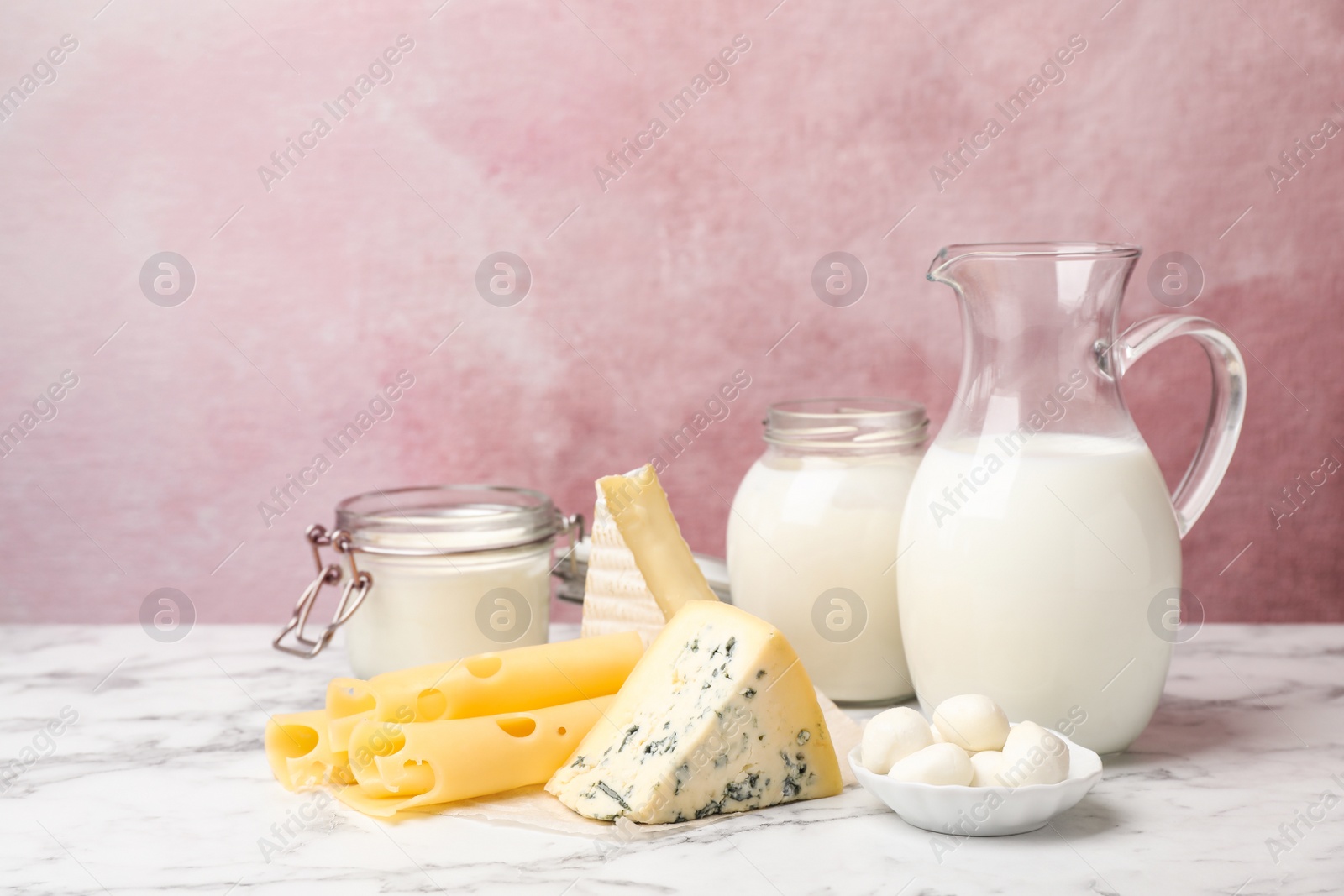 Photo of Fresh dairy products on table against color background