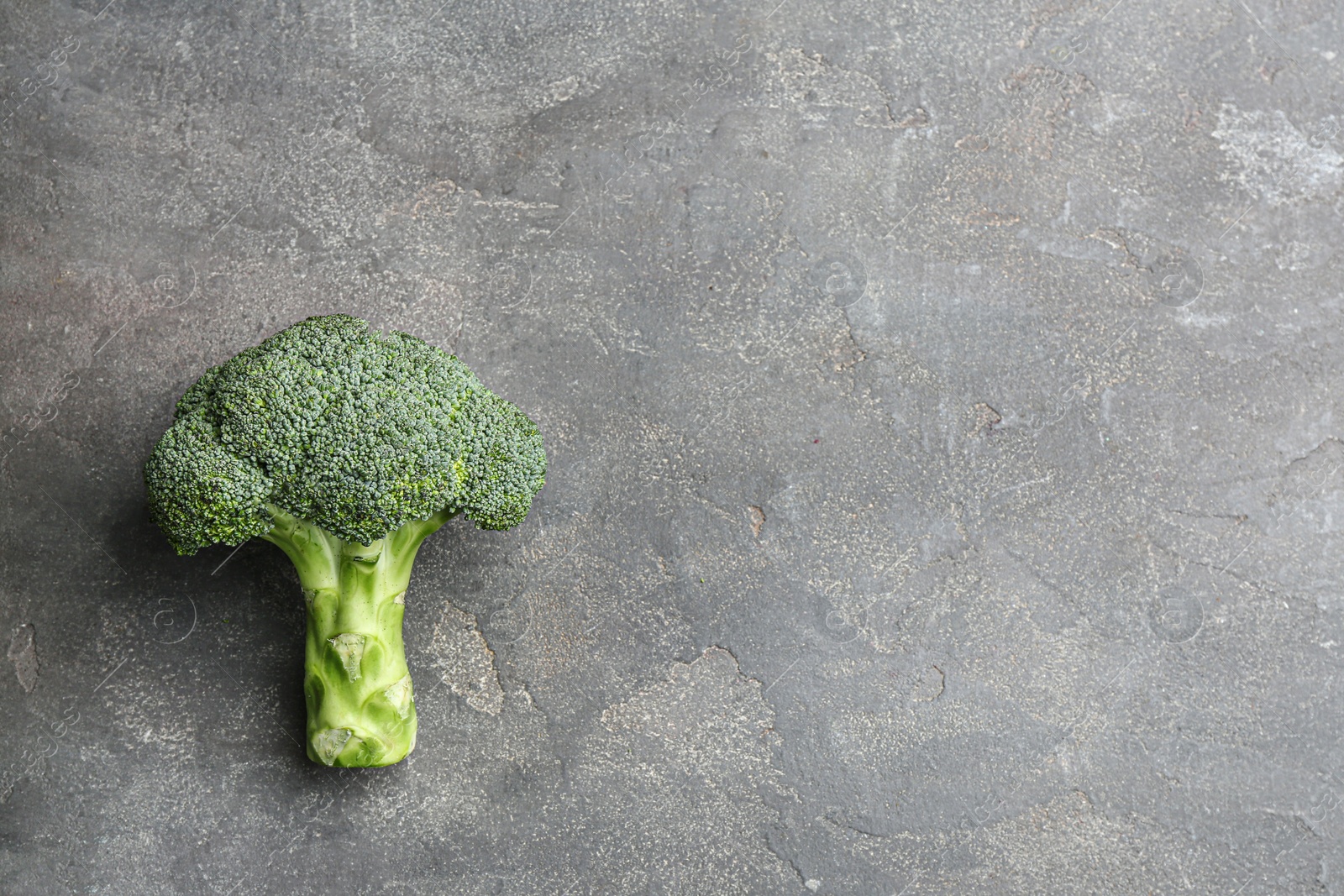 Photo of Fresh green broccoli on grey stone table, top view. Space for text