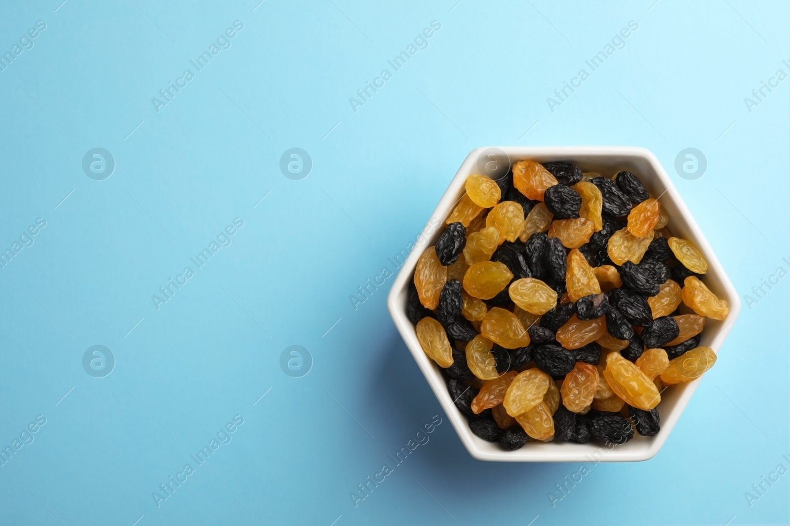Photo of Bowl of raisins on color background, top view with space for text. Dried fruit as healthy snack