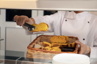 Photo of School canteen worker with basket of bread at serving line, closeup. Tasty food