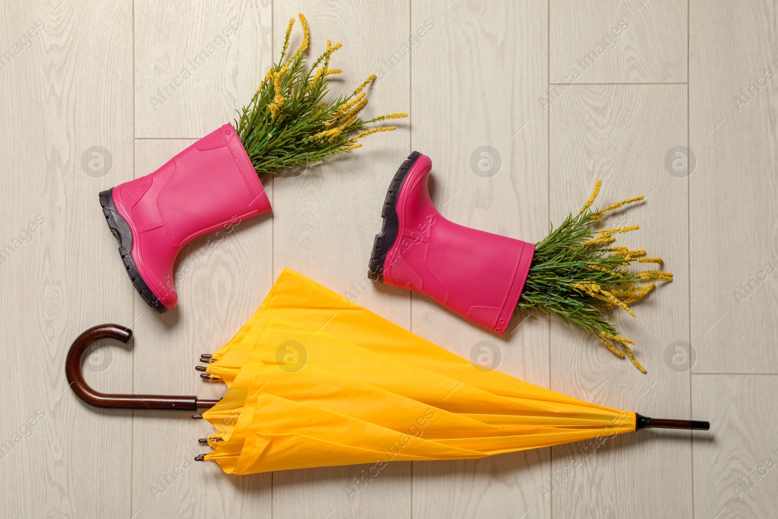 Photo of Flat lay composition with umbrella and rubber boots on wooden background