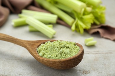 Photo of Natural celery powder in wooden spoon on grey table, closeup