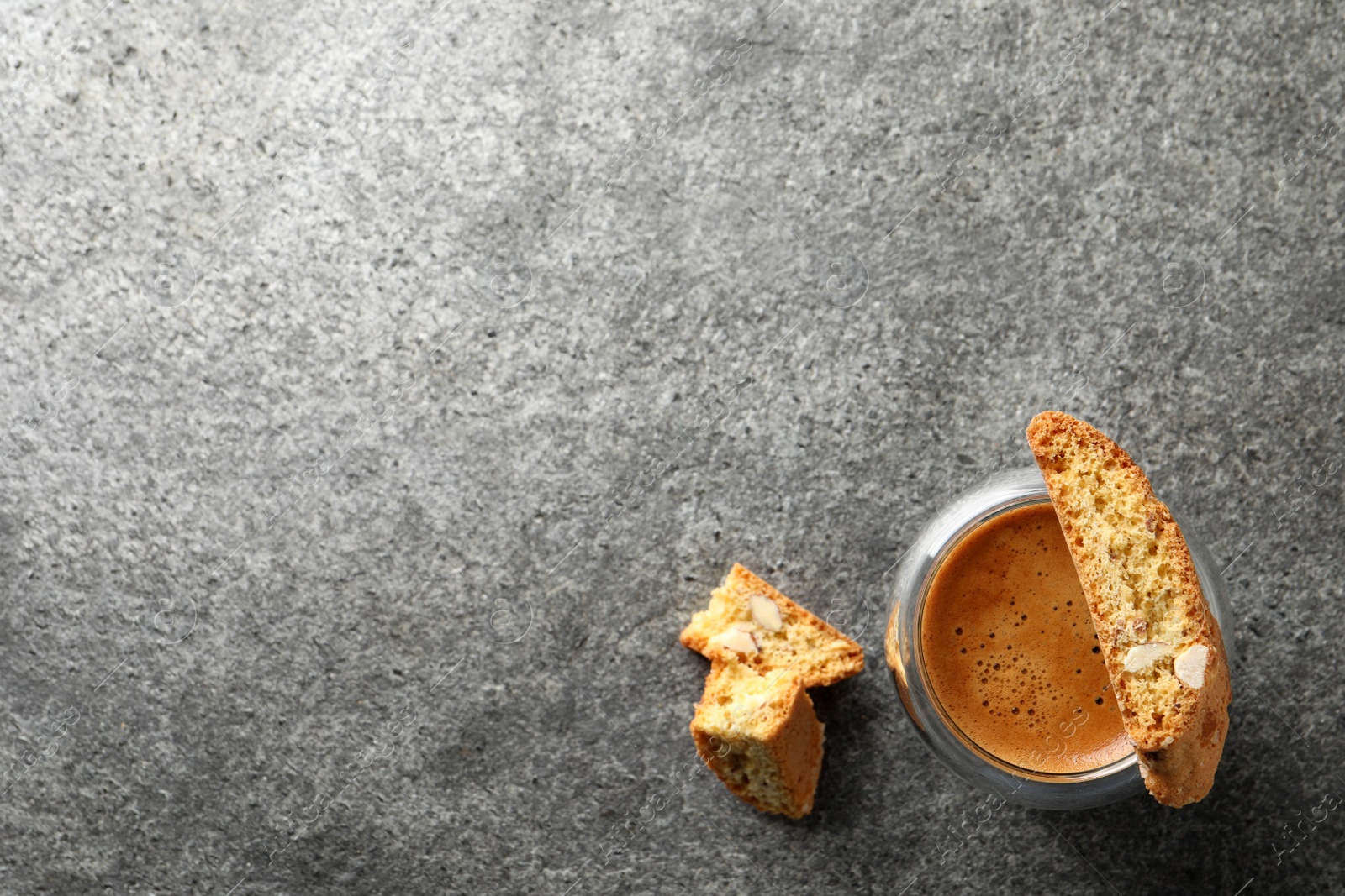 Photo of Tasty cantucci and cup of aromatic coffee on grey table, flat lay with space for text. Traditional Italian almond biscuits