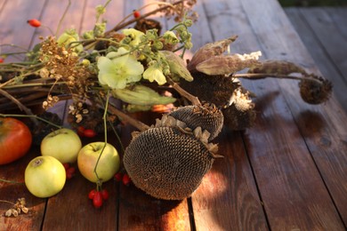 Photo of Composition with beautiful flowers, dry sunflowers and apples on wooden table outdoors, closeup. Autumn atmosphere