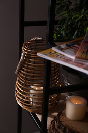 Photo of Stylish holder with burning candle, houseplant and decor on shelving unit near grey wall