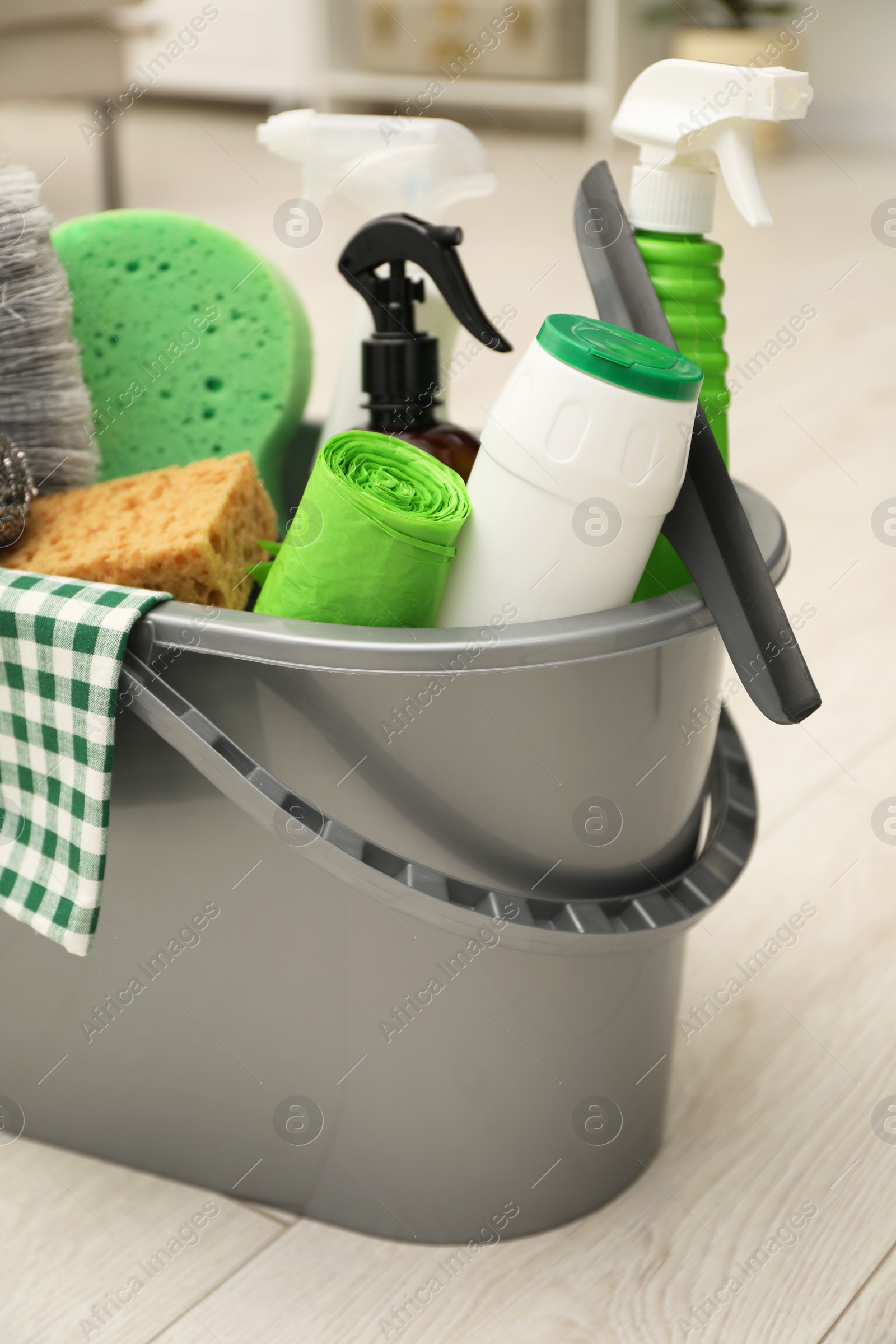 Photo of Different cleaning supplies in bucket on floor at home