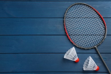 Racket and shuttlecocks on blue wooden table, flat lay with space for text. Badminton equipment