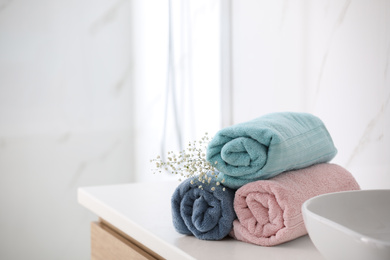 Photo of Rolled fresh towels on countertop in bathroom. Space for text