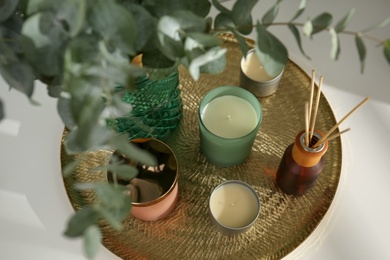 Photo of Eucalyptus branches, aromatic reed air freshener and candles on white table indoors, above view. Interior element