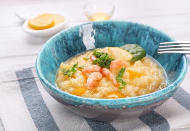 Bowl with tasty shrimps and grits on table