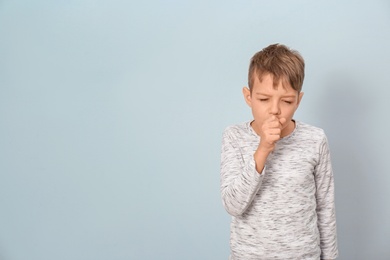 Photo of Little boy coughing on light background