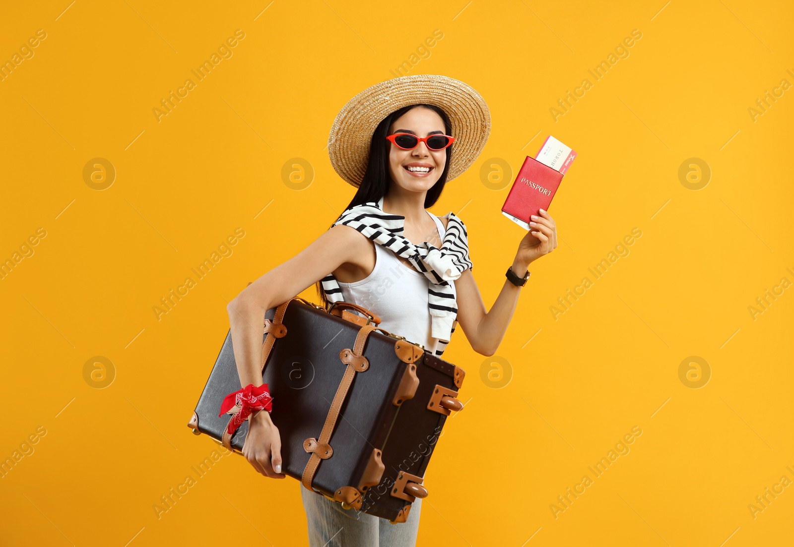 Photo of Happy female tourist with passport, ticket and suitcase on yellow background