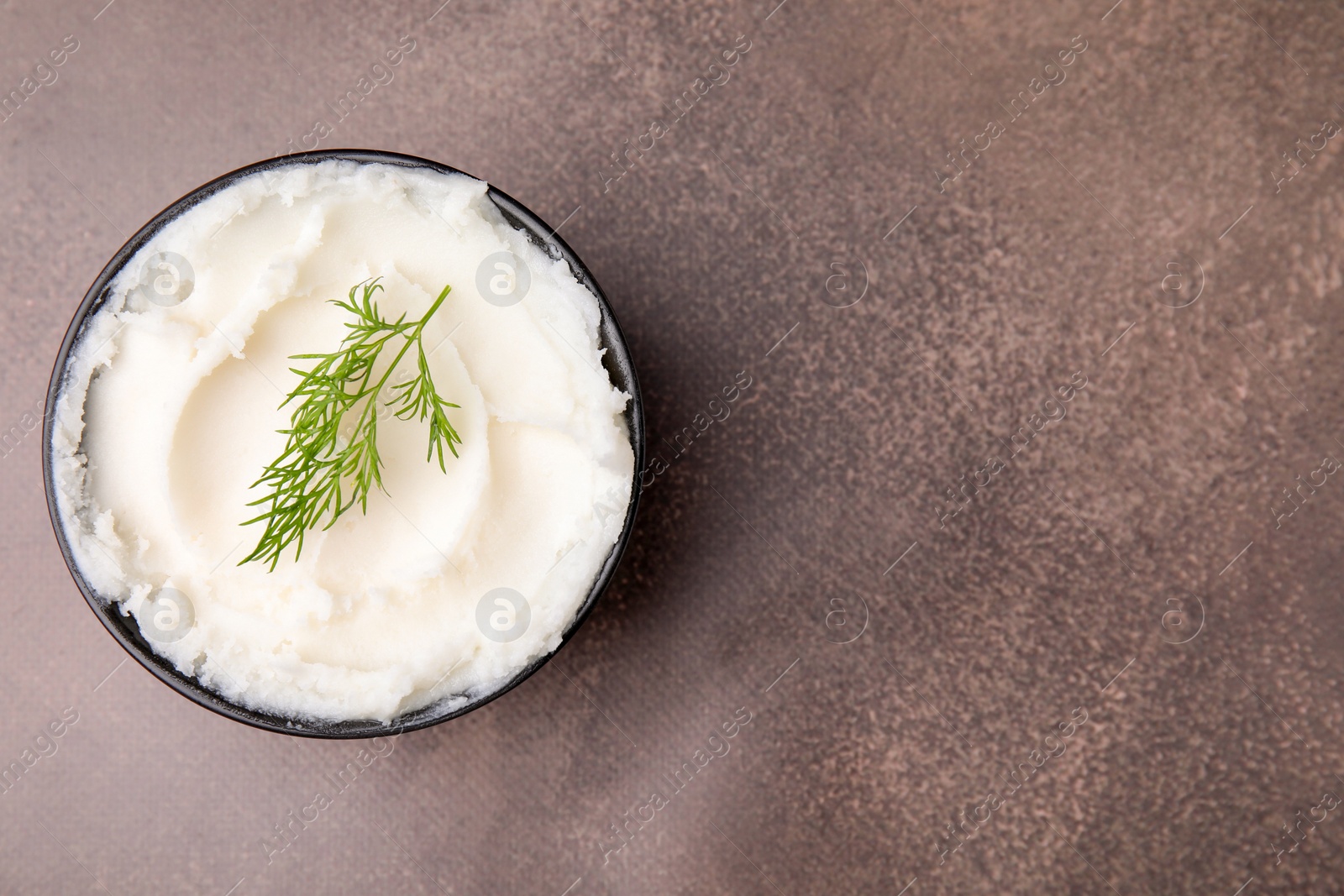Photo of Delicious pork lard with dill in bowl on brown table, top view. Space for text