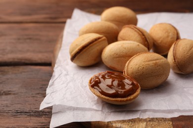 Delicious nut shaped cookies with boiled condensed milk on parchment paper, closeup