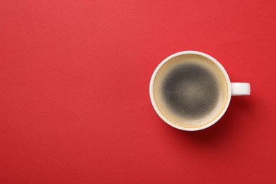 Photo of Aromatic coffee in cup on red background, top view. Space for text