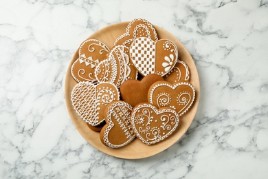 Tasty heart shaped gingerbread cookies on white marble table, top view