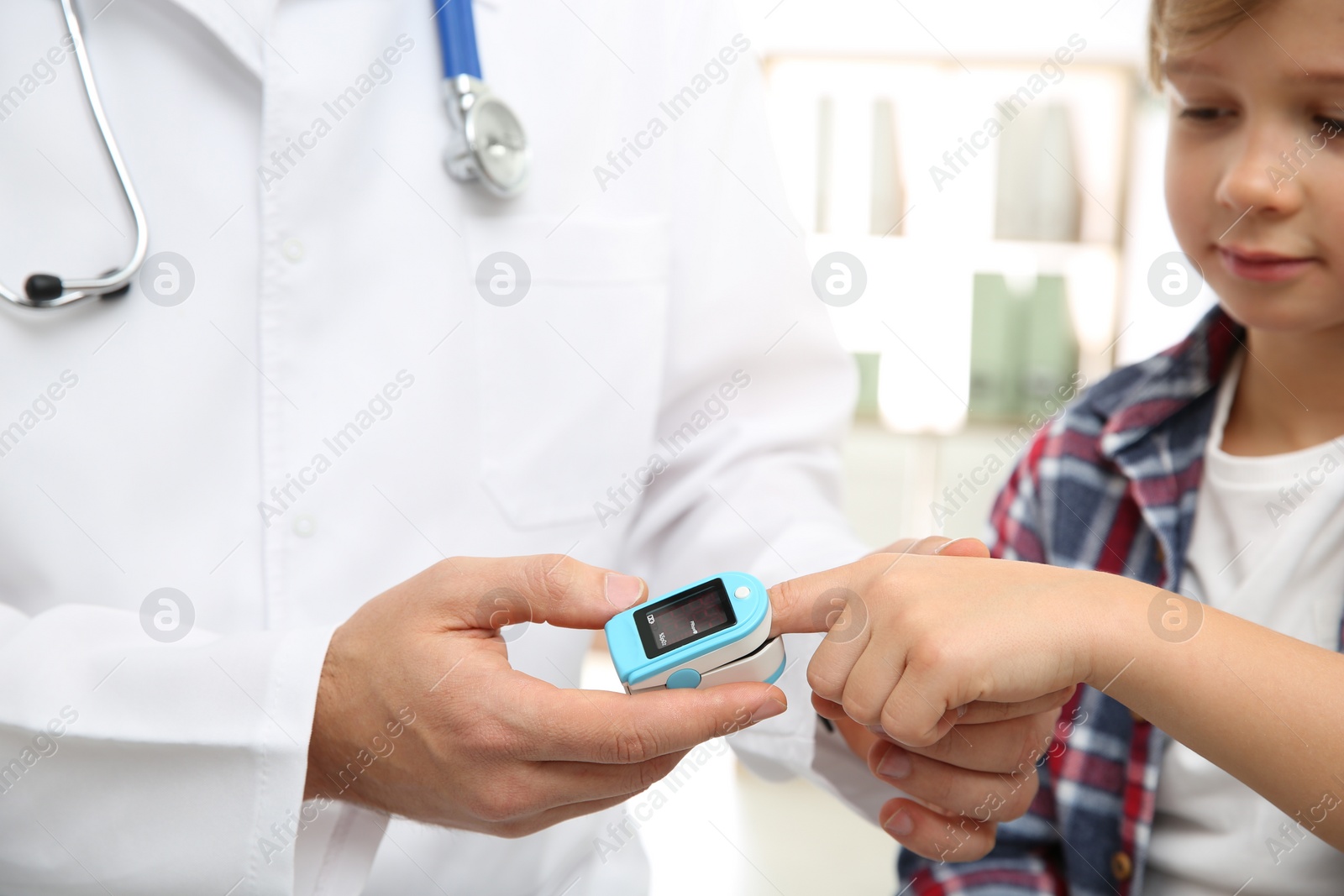 Photo of Doctor checking little boy's pulse with medical device indoors, closeup