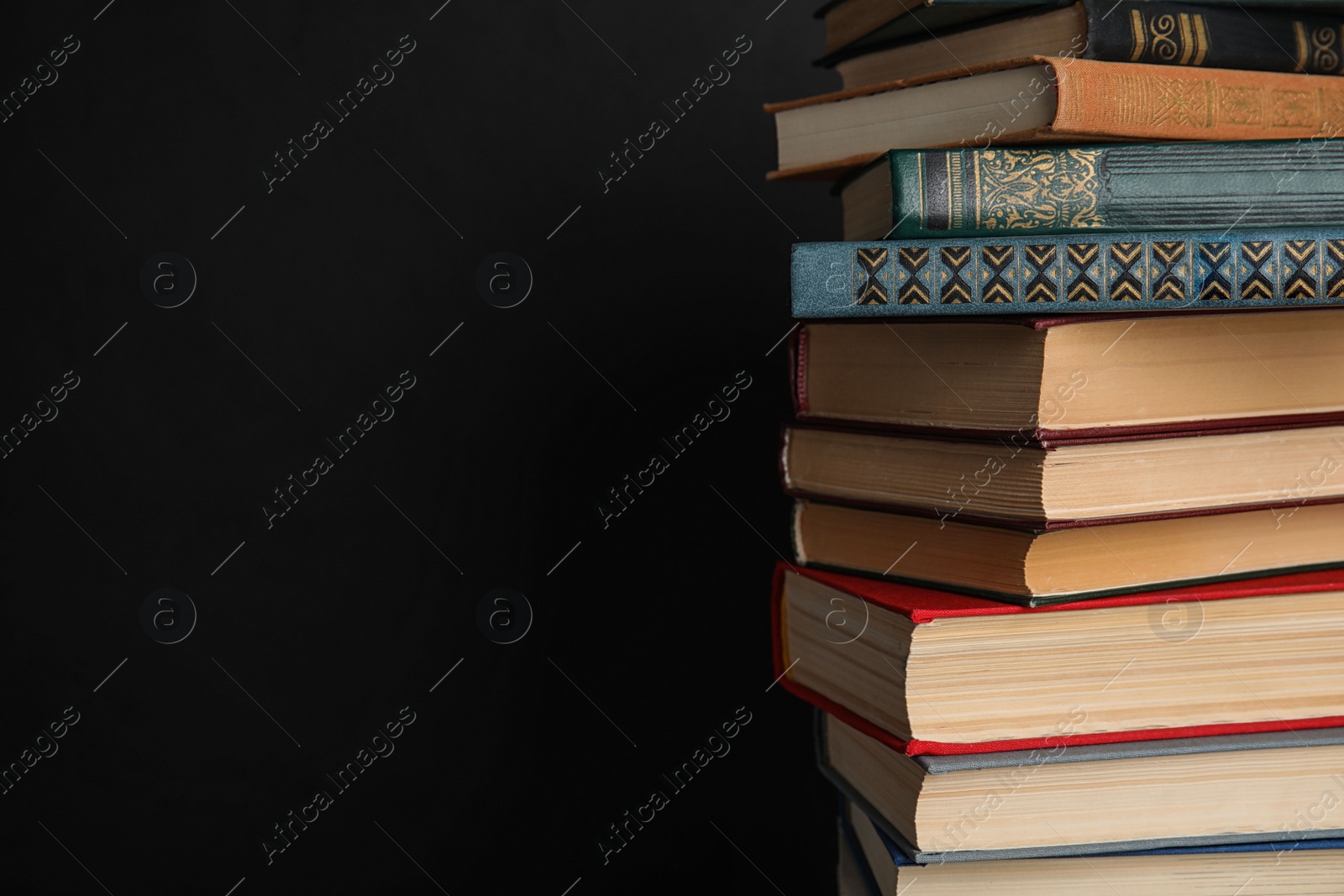 Photo of Stack of hardcover books on black background. Space for text