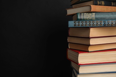 Photo of Stack of hardcover books on black background. Space for text