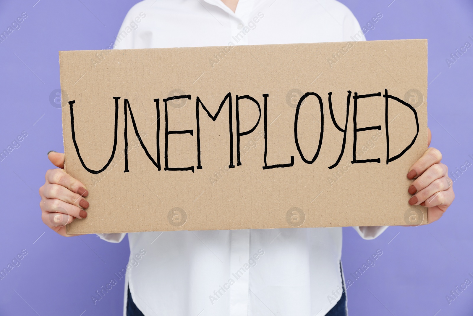 Photo of Young woman holding sign with word Unemployed on violet background, closeup