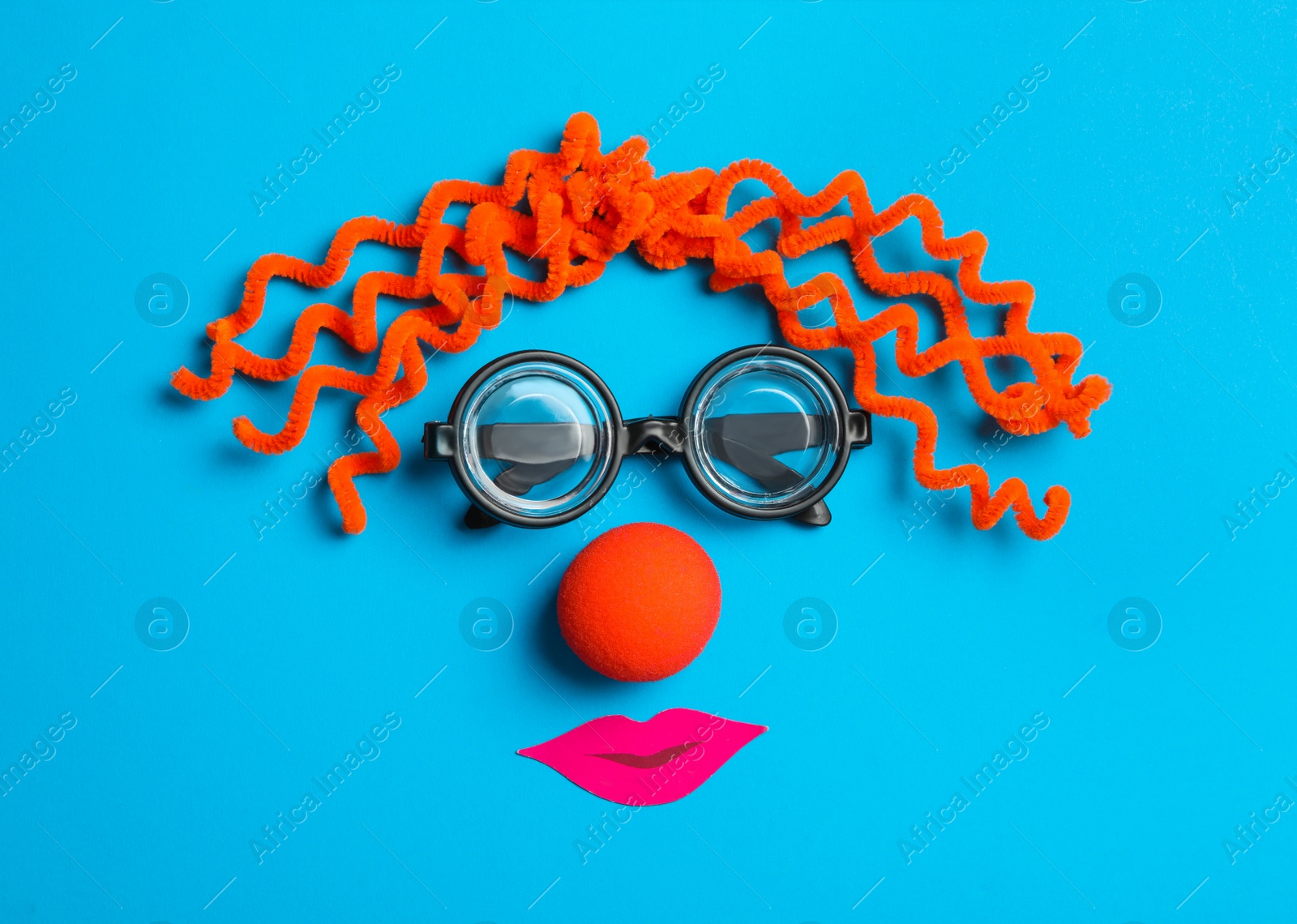 Photo of Funny face made with clown's accessories on light blue background, flat lay