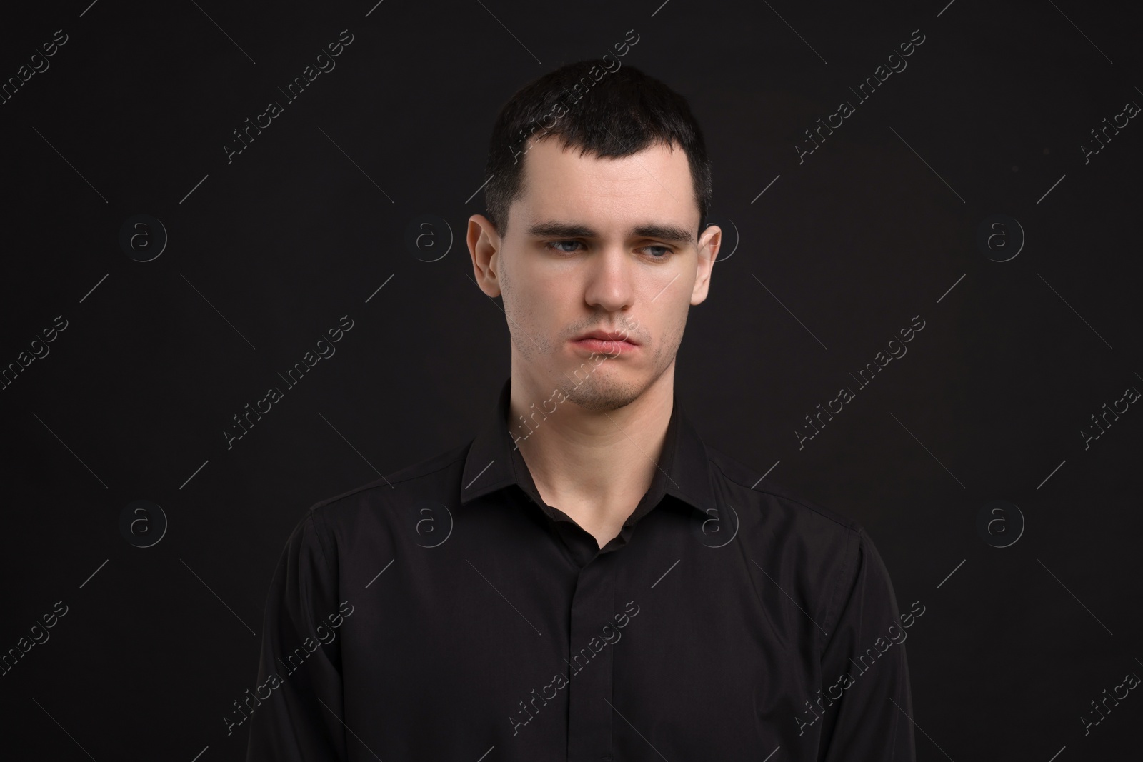 Photo of Portrait of sad man on black background