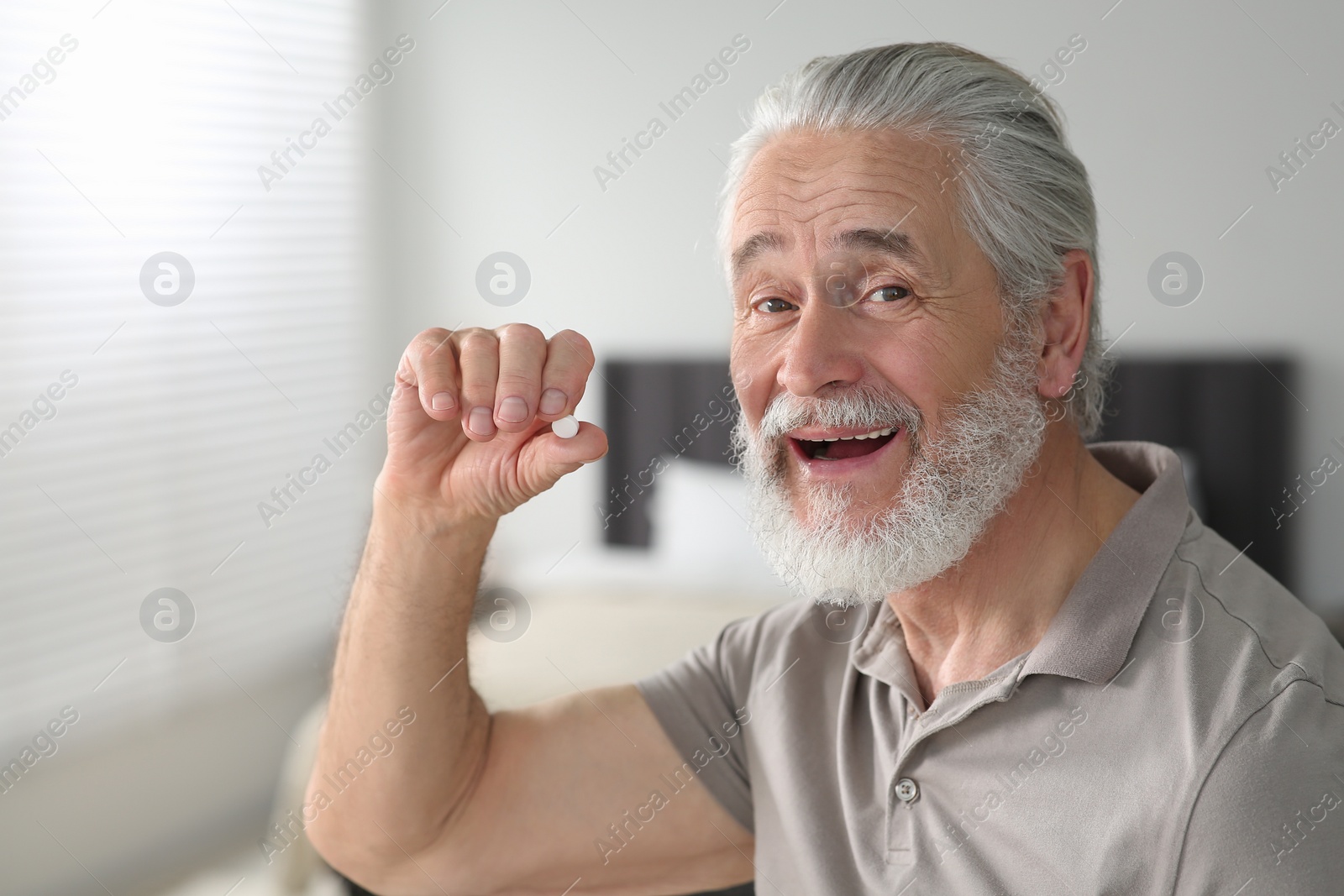 Photo of Handsome senior man with pill at home
