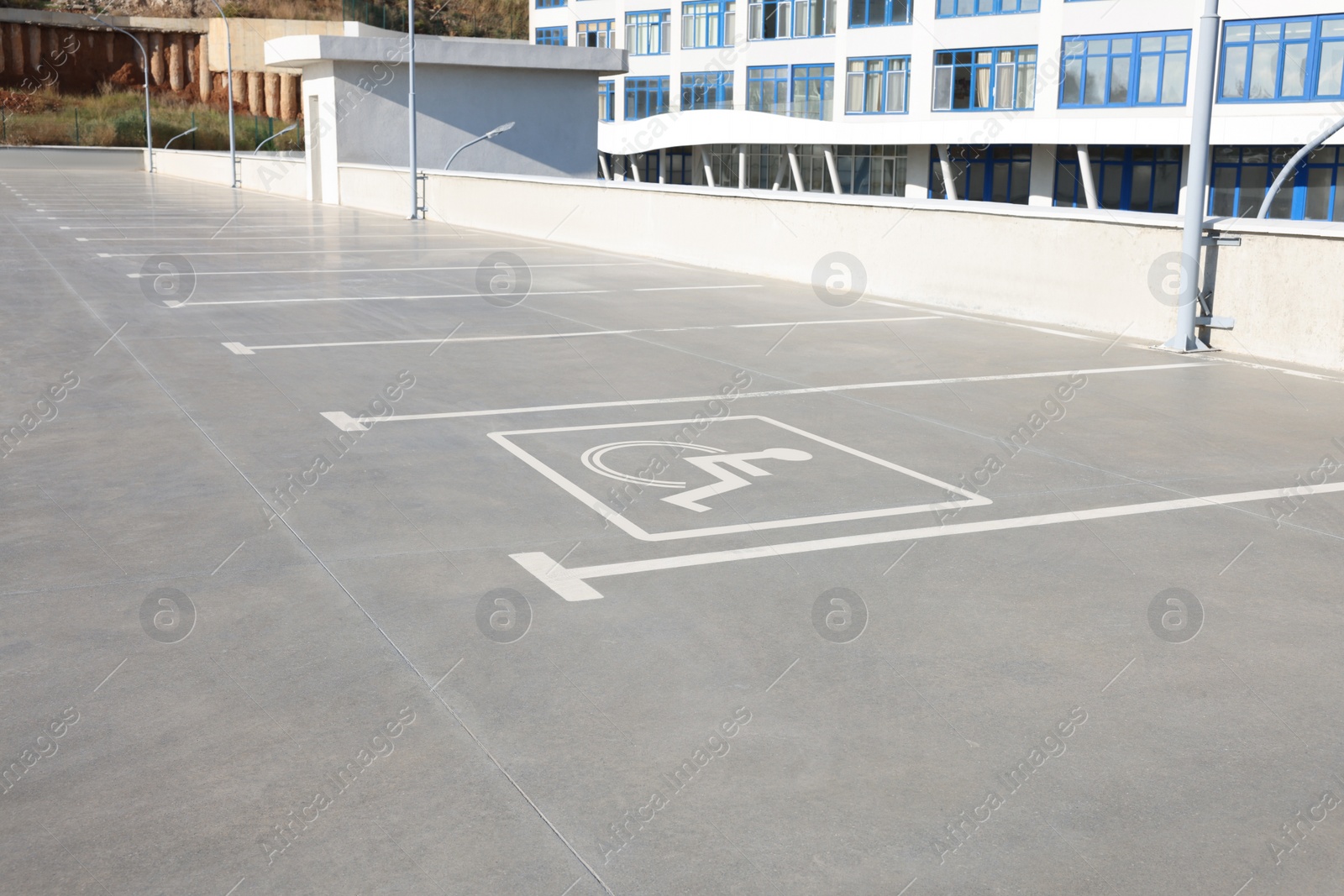 Image of Car parking lot with white marking lines and wheelchair symbol outdoors 