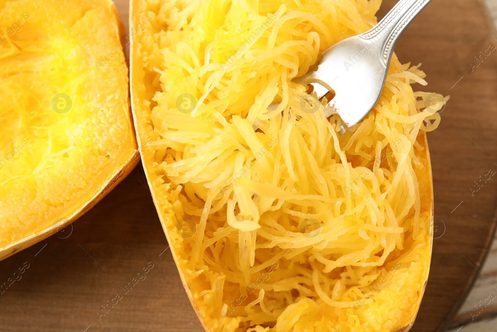 Photo of Cooked spaghetti squash and fork on wooden board, top view