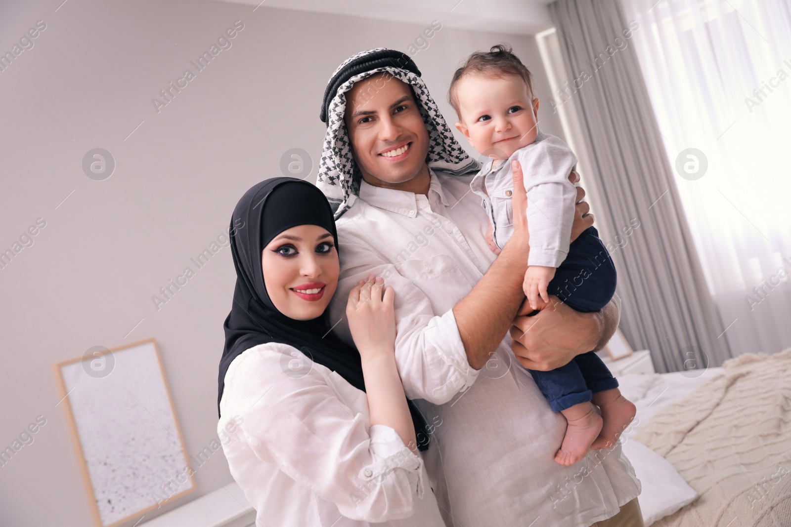 Photo of Happy Muslim family with little son in bedroom