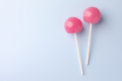 Photo of Tasty lollipops on light blue background, flat lay. Space for text