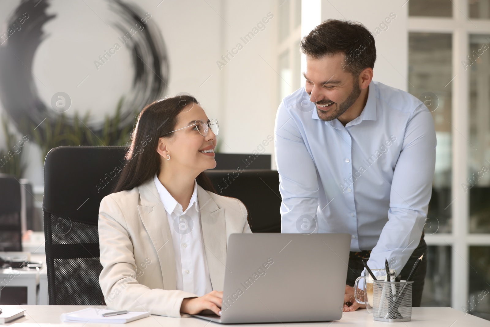 Photo of Colleagues working on laptop at desk in office