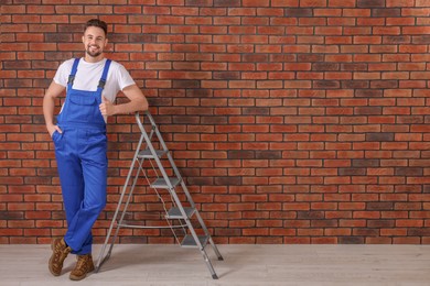 Photo of Happy worker showing thumb up near stepladder against brick wall, space for text