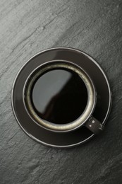 Hot coffee in cup on dark textured table, top view