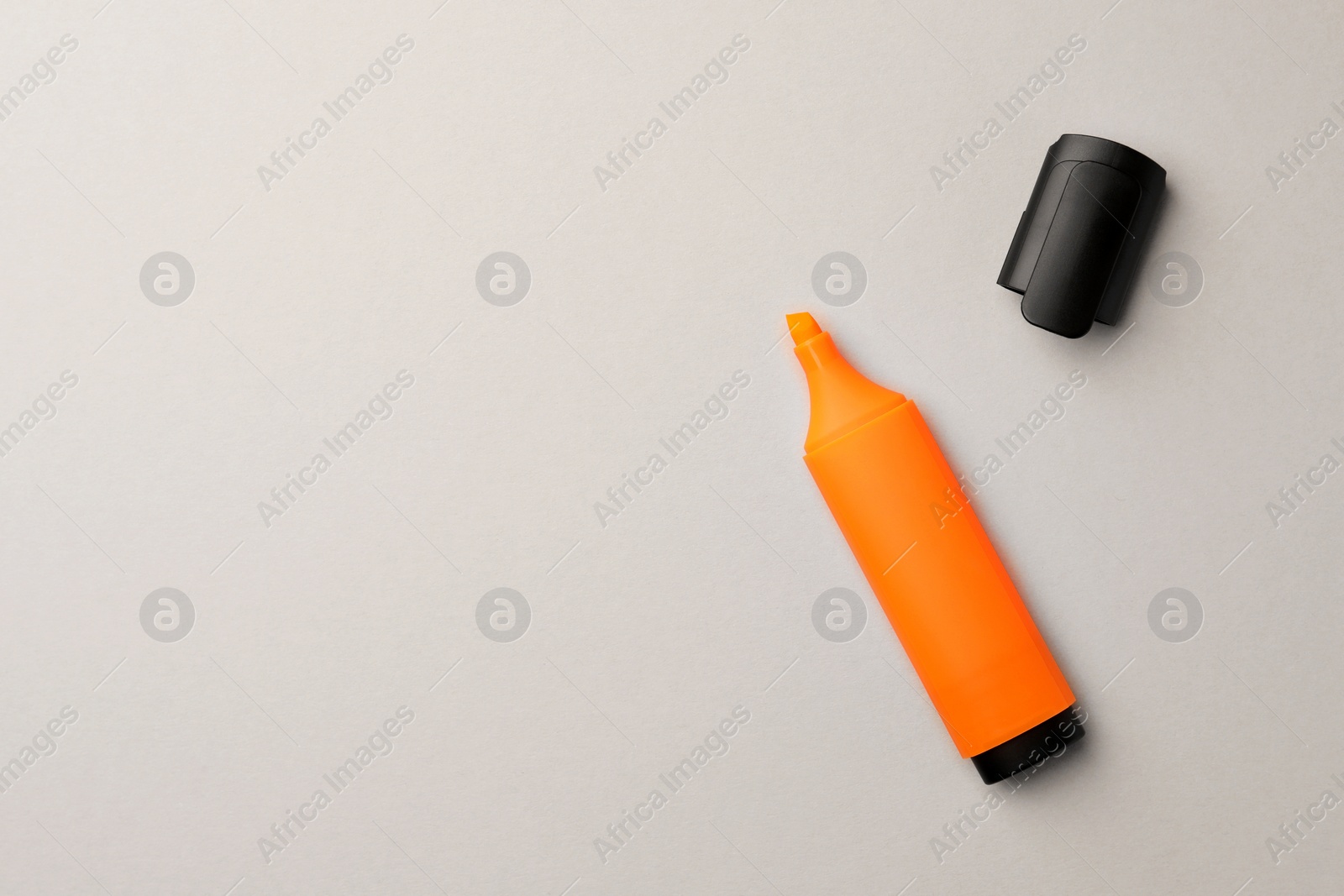 Photo of Bright orange marker on light grey background, flat lay. Space for text