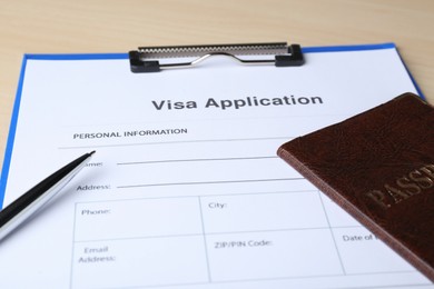 Photo of Visa application form for immigration, passport and pen on table, closeup