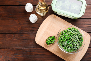 Flat lay composition with frozen green peas on wooden table. Vegetable preservation