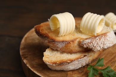 Tasty butter curls and slices of bread on wooden table, closeup