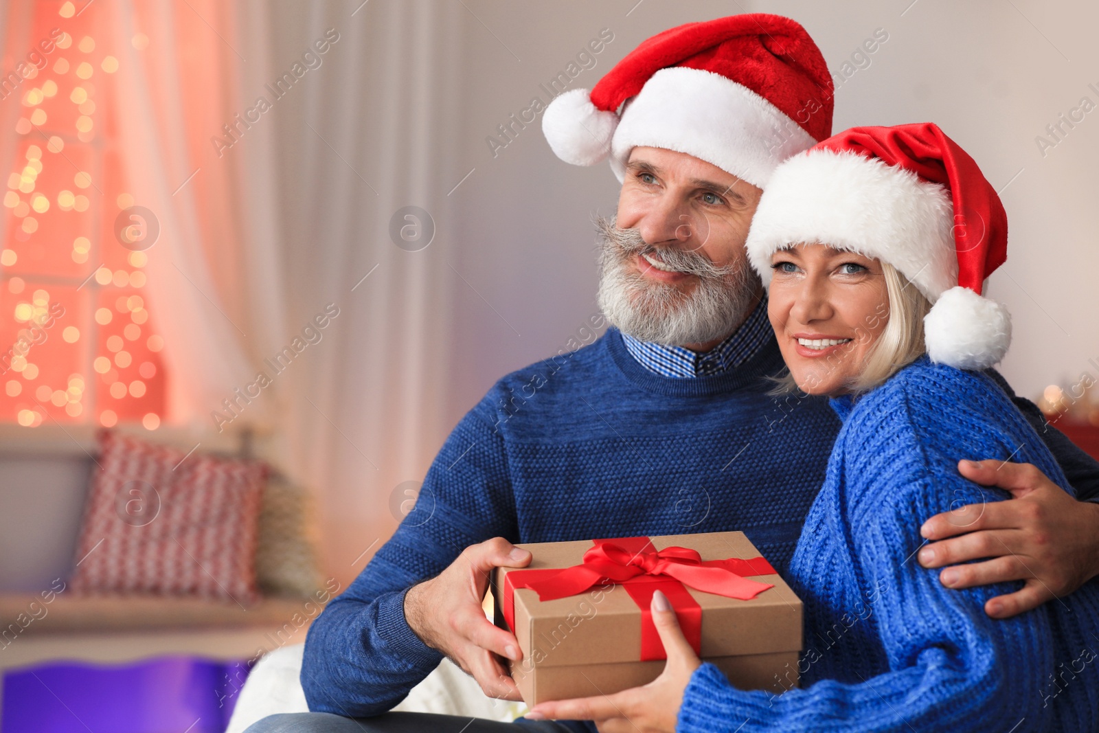 Photo of Happy couple opening Christmas gift at home