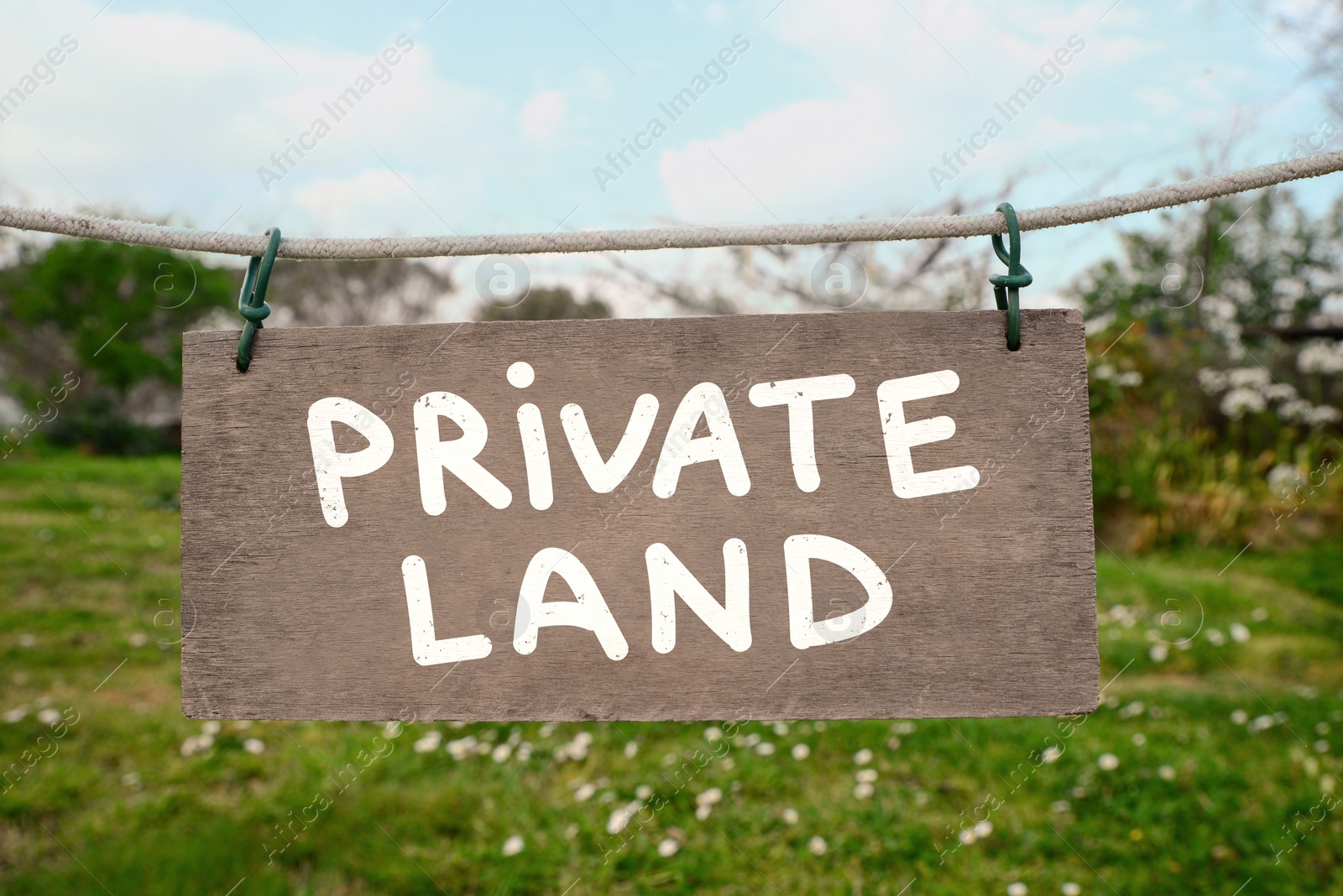 Image of Sign with text Private Land hanging on rope outdoors
