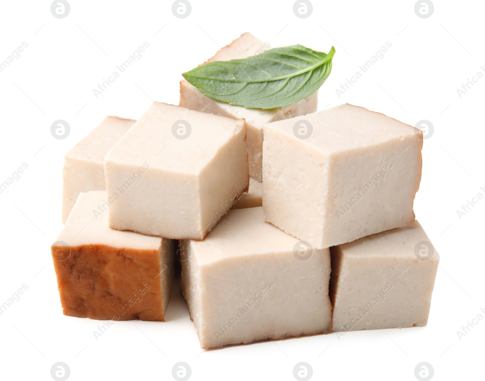 Photo of Pile of smoked tofu cubes and basil on white background